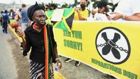 AFP via Getty Images People calling for slavery reparations, protest outside the entrance of the British High Commission during the visit of the Duke and Duchess of Cambridge in Kingston, Jamaica on 22 March 2022