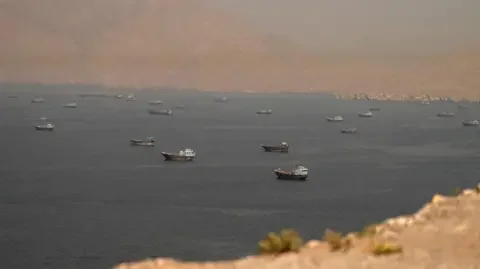 Reuters Dozens of vessels are seen in the Strait of Hormuz, surrounded by rocky mountains, from Musandam, Oman