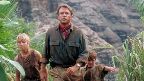 Getty Images Sam Neill walking through a Jurassic forest, leading two children