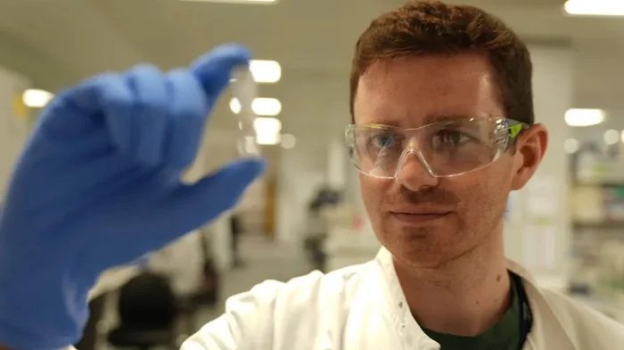 Researcher Alex Sampson holds the experimental Ebola vaccine