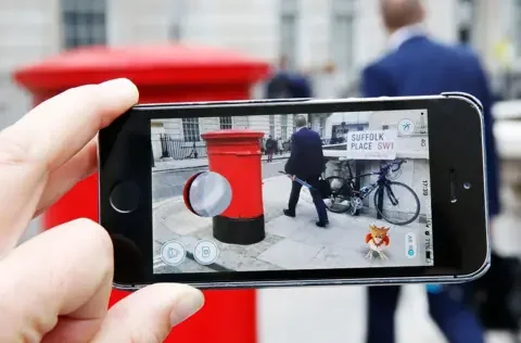 Getty Images A phone held horizontal with the Pokémon Go game running over a UK address of Suffolk place. A Spearow sits in the corner on the phone.