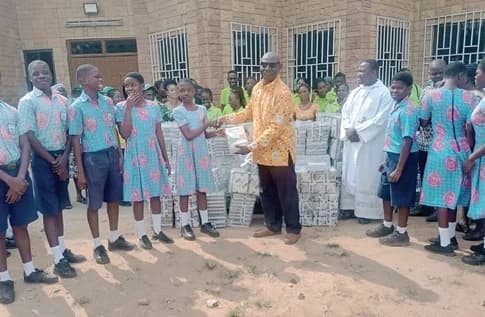 Rev. Peter Ankrah Doodoo, Manager of Shalom D Susu Enterprise, presenting the books to one of the students