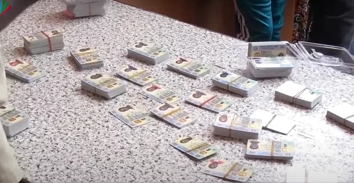Multiple stacks and individual Ghana Cards are spread across a speckled gray tabletop, some held together by rubber bands. The photo highlights the biometric identification cards issued by the National Identification Authority (NIA) during a registration exercise.