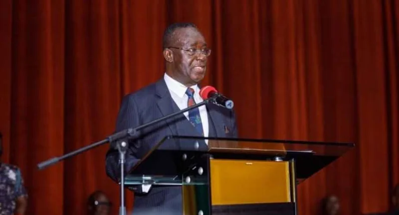 Justice Kwasi Anin-Yeboah, a prominent Ghanaian judicial figure, is shown delivering a formal address from a podium. He is wearing a dark suit and glasses while speaking into a microphone against a backdrop of deep red curtains at what appears to be a legal ceremony.