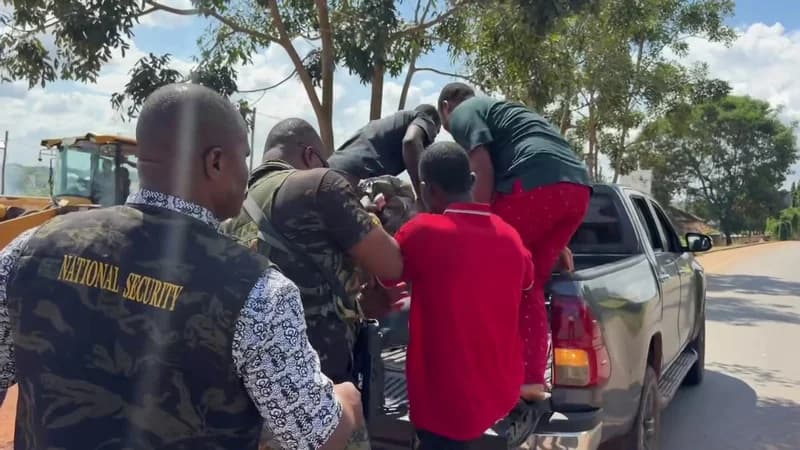 National Security personnel in Ghana are seen apprehending individuals and loading them into the back of a grey pickup truck along a roadside. A yellow earthmoving machine is visible in the background, suggesting an enforcement operation against illegal activities like sandwinning as mentioned in the news context.