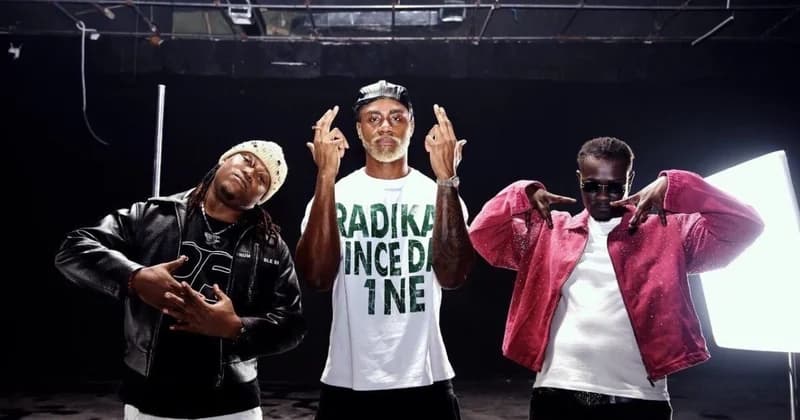 Three musicians from the BLR Boys and featuring artist 6uff pose for a promotional photo in a studio setting. The artists are dressed in urban streetwear, including leather and denim jackets, while making expressive hand gestures against a dark background with studio lighting visible.