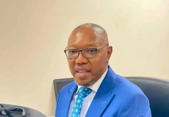 A portrait of Dr. Clement Apaak, a prominent Ghanaian Member of Parliament and education advocate. He is depicted wearing a blue suit, white shirt, and a patterned blue tie while speaking in a formal setting with a plain background.
