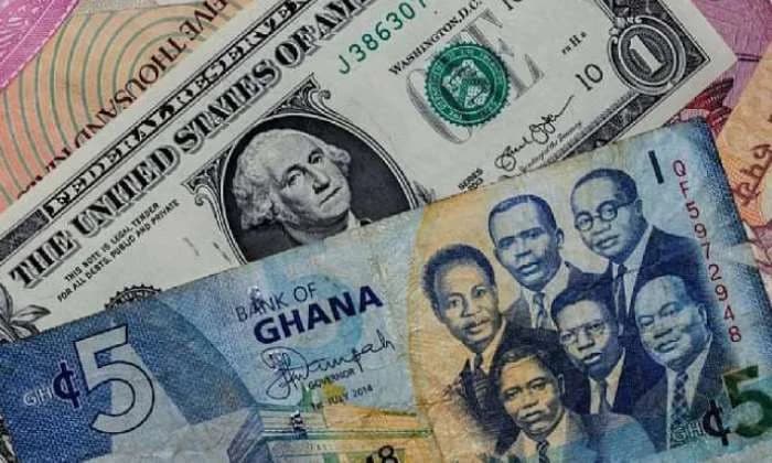 A close-up photograph showing a mixture of Ghanaian Cedi and United States Dollar banknotes. A blue 5 Cedi note featuring the 'Big Six' founding fathers is prominently displayed alongside a US One Dollar bill showing George Washington.